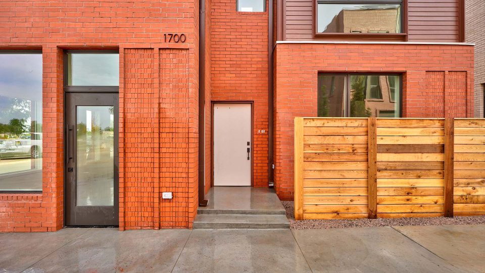 a brick building with a wooden fence and a door at The Spoke Street Apartments